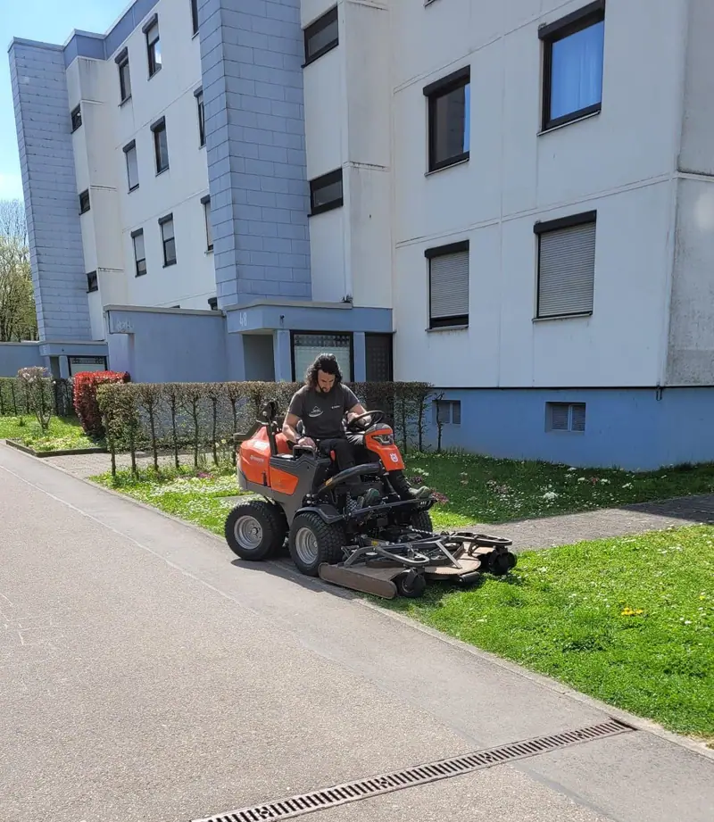 Bojan Kabic beim Rasenmähen mit dem Aufsitzmäher an einer Wohnanlage in Ludwigsburg