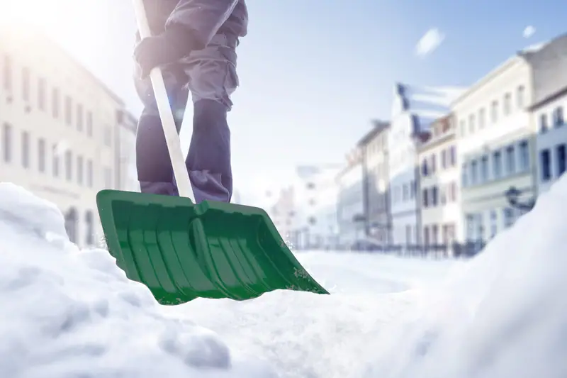 Winterdienst: Schneeräumen auf dem Gehweg mit der Schneeschaufel